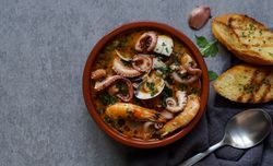 Soup of octopus and shrimps near toasts and spoon