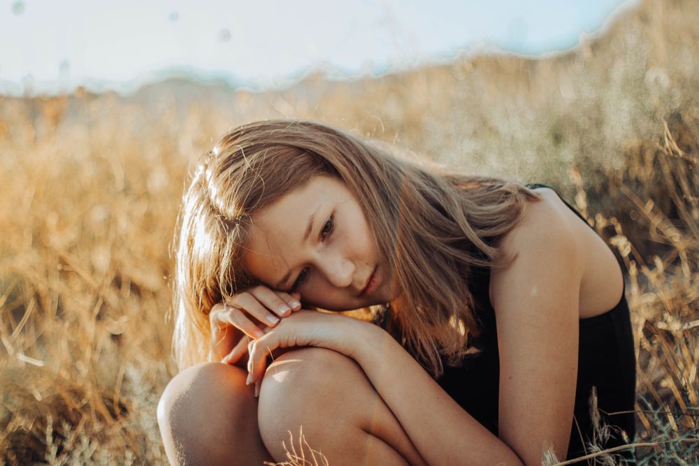 Girl sitting on yellow grass field