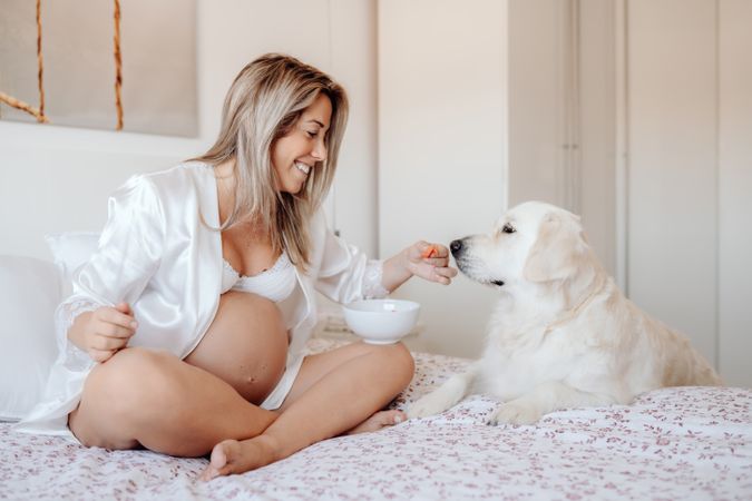 Pregnant woman eating fruits and resting with dog
