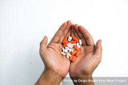 Hands holding variety of colorful medication and vitamins with plain background beXoZp