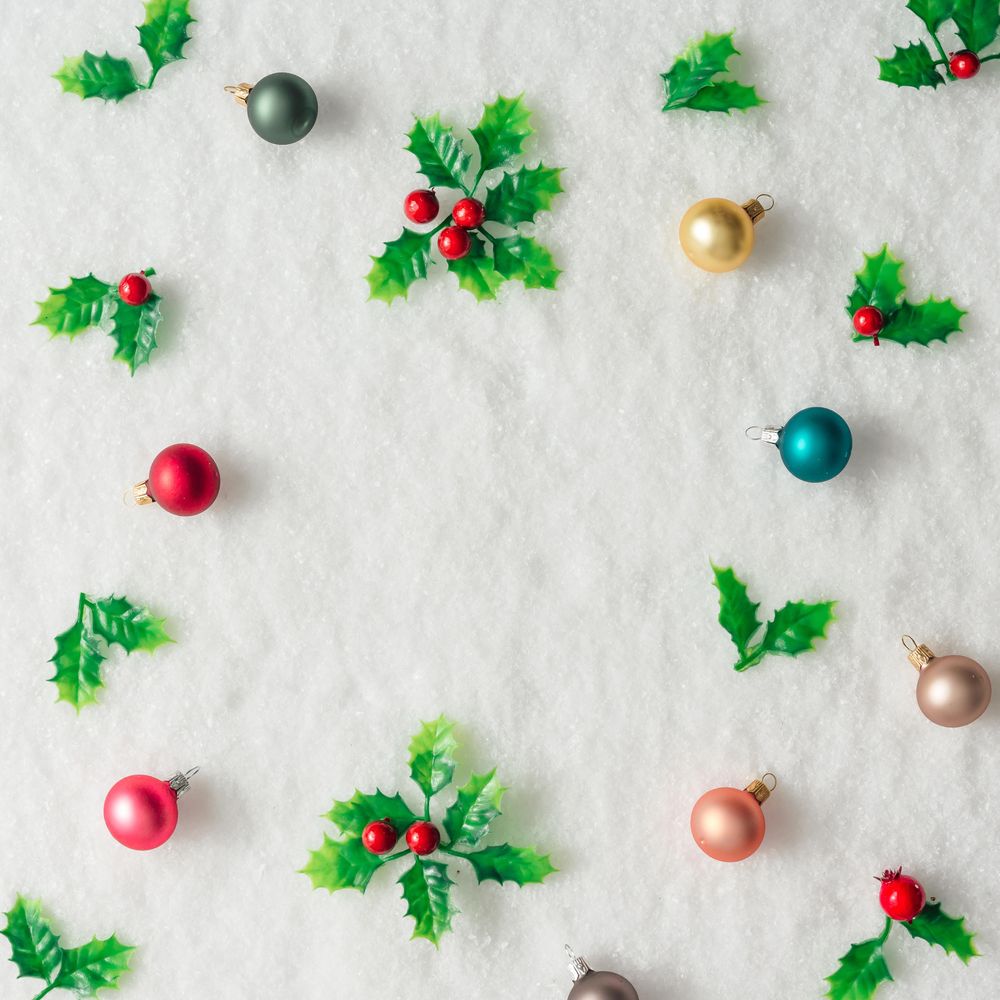 Pattern of plastic holly and baubles on snow background