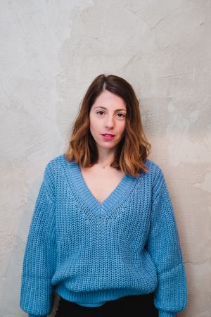 Charming woman in sweater near wall