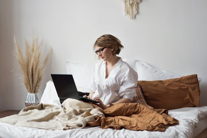 Woman Working From Home In Bed With Laptop