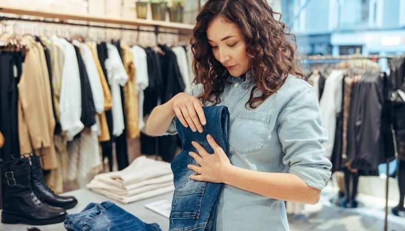 Boutique owner folding jeans on table
