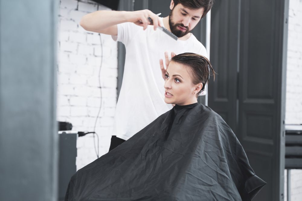 Hairdresser cuts woman's hair with scissors