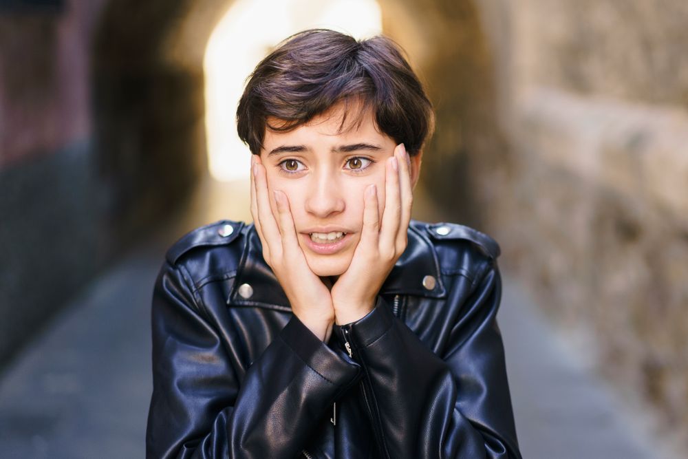 A Young Individual Wearing a Leather Jacket Conveying Strong Emotions in an Alleyway