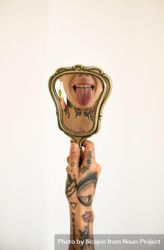 Tattooed woman holding hand mirror 4Nxvm0