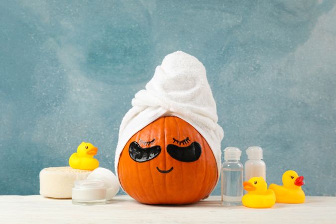 Skincare accessories and pumpkin with eye patches on blue background