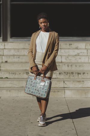 Stylish Black woman with handbag near steps on street