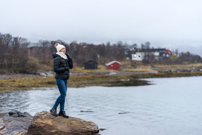Female standing on stone cliff off coast