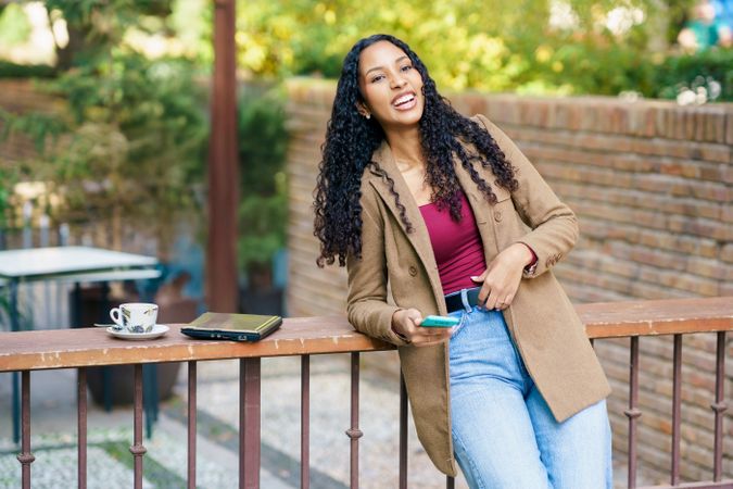 A Joyful Young Woman is Enjoying a Cup of Coffee Outdoors in a Lively Atmosphere and Sunshine