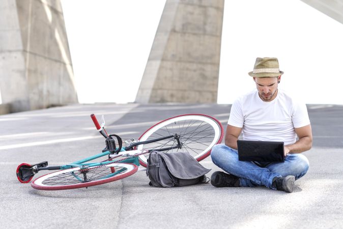 Male sitting outdoors with bicycle and laptop