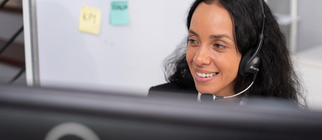 Smiling hispanic employee working at desk to support customers in the office