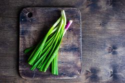 Fresh green onions on wooden board