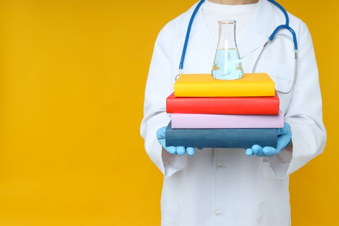 Flask, books and doctor on yellow background, space for text