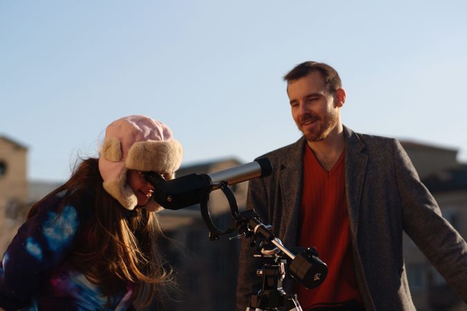 Young astronomy learner observes sun, guided by teacher on rooftop