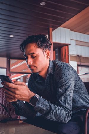 South Asian man in dress shirt holding smartphone