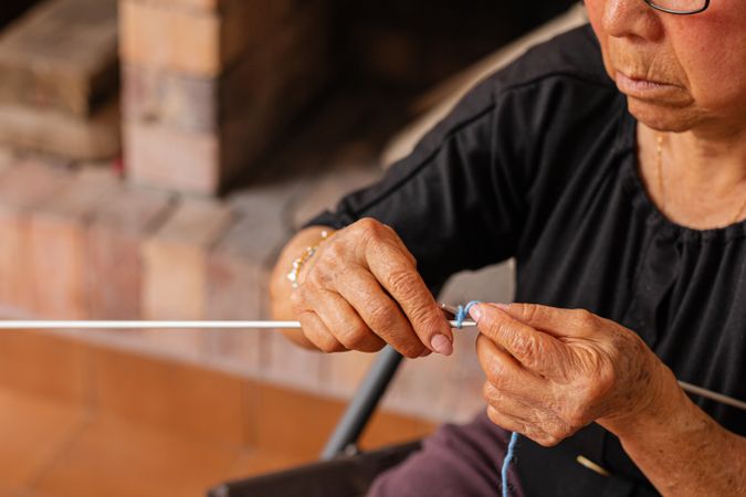 Artful aging. Latina woman knits with grace.