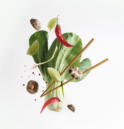 Asian food concept with flying ingredients: Bok choy , chopsticks, lime, shiitake, spices and chili