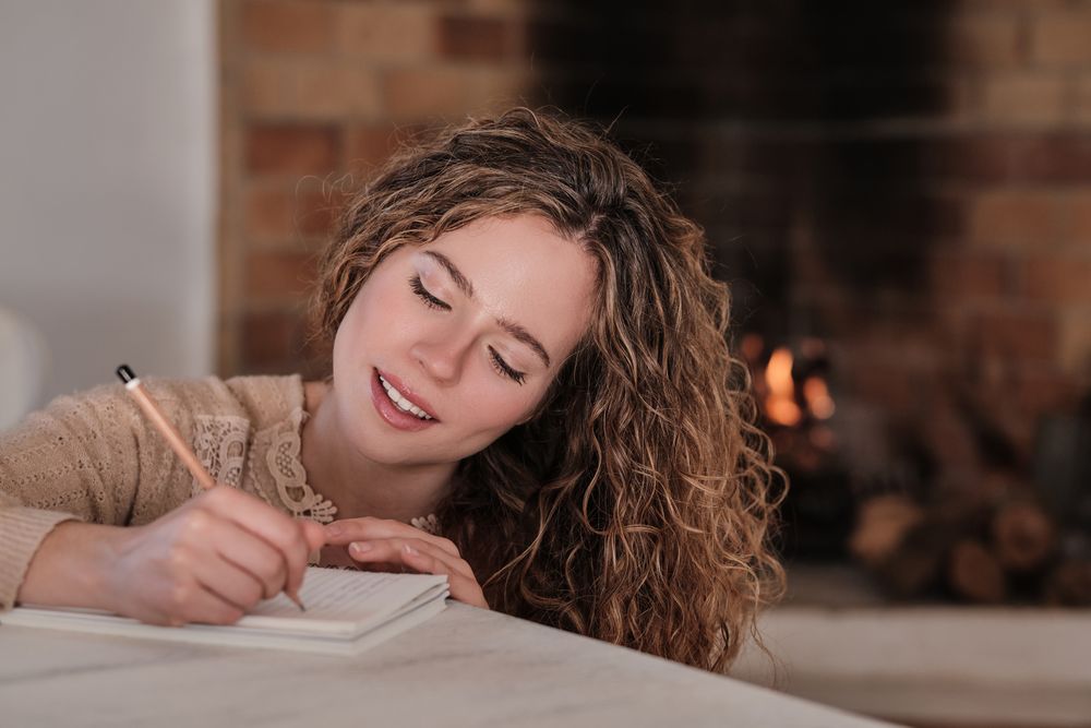 Smiling young female writing in diary