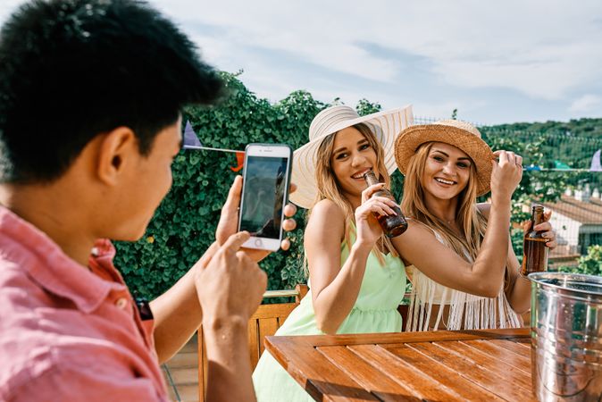 a young man takes a selfie of two blond women
