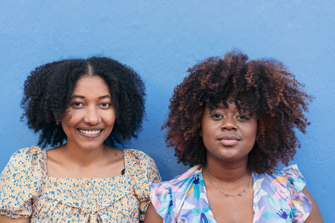 Portrait of two women standing on a blue wall