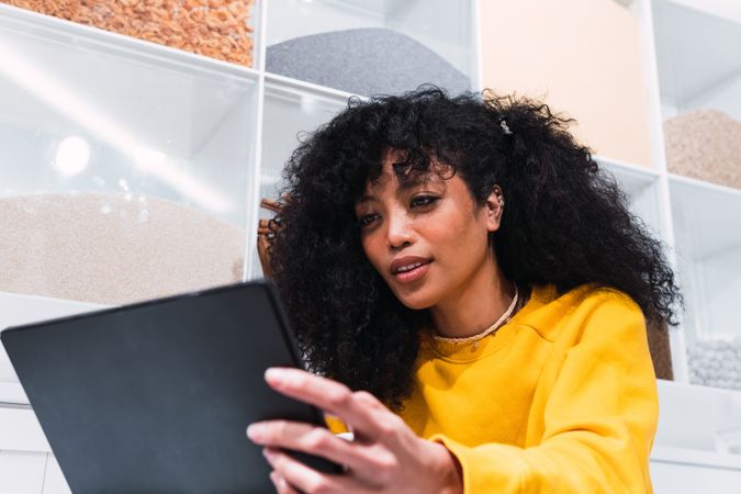 Black woman using tablet against wall