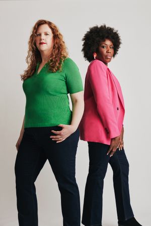 Two women standing back to back in bright clothes