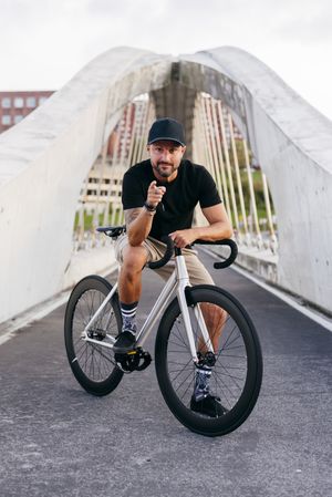 Cheerful man with bicycle standing on footbridge