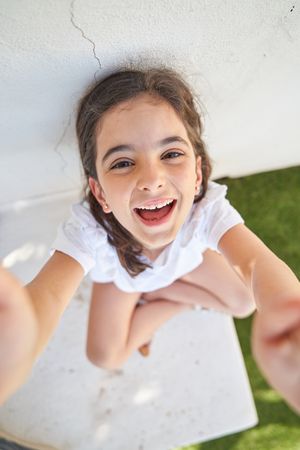 Excited girl sitting near concrete wall
