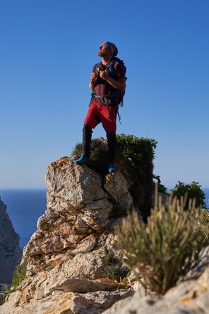 Male hiker with backpack standing on rocky cliff