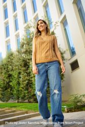 Woman in jeans and vest walking outside 0v38yd
