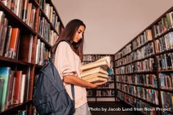 Young woman holding textbooks while reading book in library 41N2gb