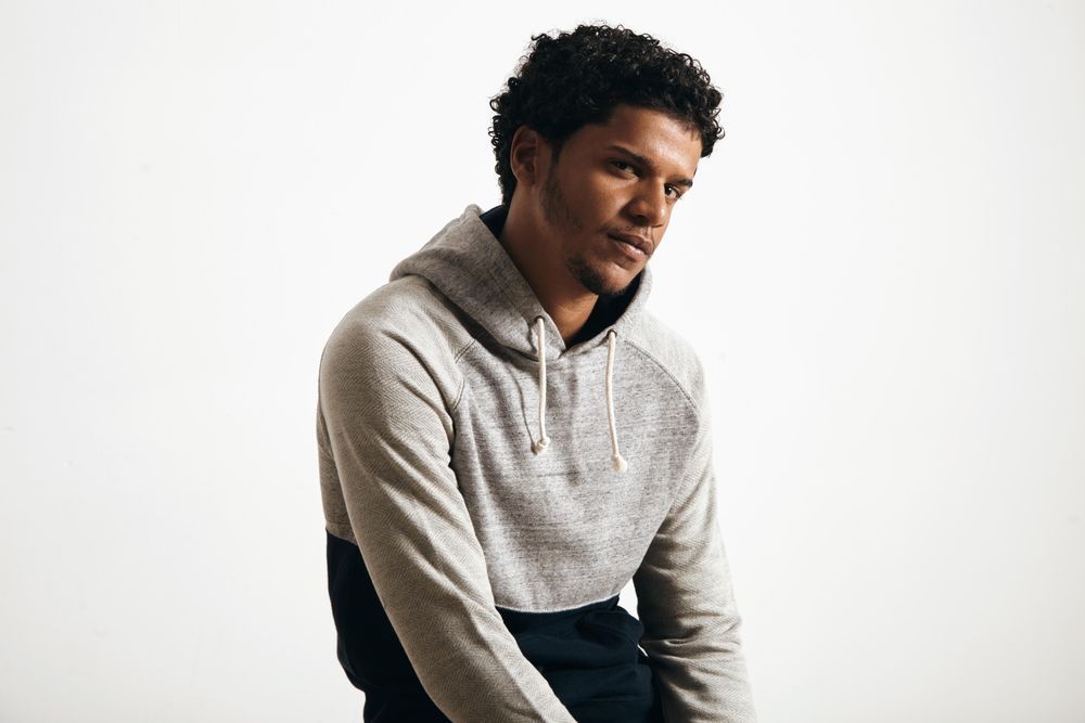 Man in grey hoodie looking thoughtfully into camera