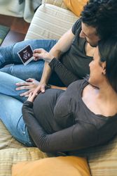 Pregnant with her partner looking at ultrasound of their baby
