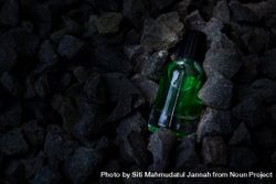 Green perfume bottle mock up laying in rocky terrain 4NEazm