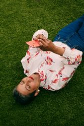 Woman laying on her back while looking a mobile phone outside