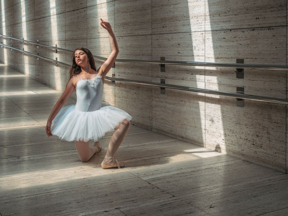 Ballerina doing ballet posing at rail in classroom