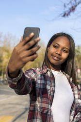 Female taking selfie with park in background, vertical