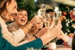 Group of happy friends laughing and toasting with champagne at a Christmas party.