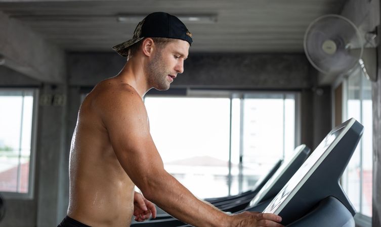 Man in with backwards cap beginning treadmill workout