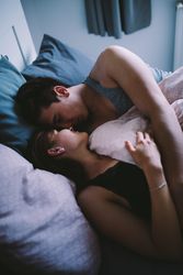 Young man and woman embrace in bed