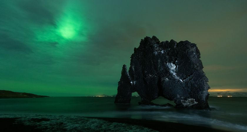 Rocky shoreline of sea under northern lights in Iceland