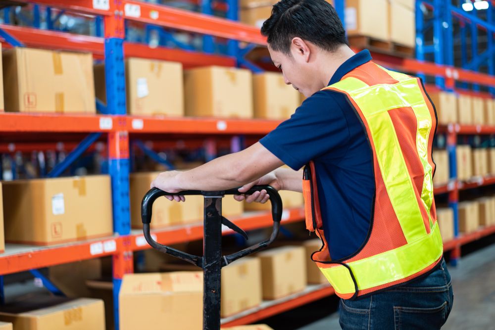 Man in front of boxes stacked on shelves in store house