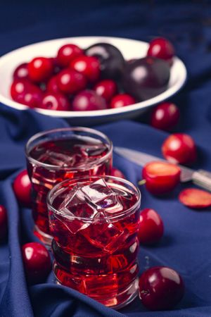 Red beverage near fresh fruits on cloth