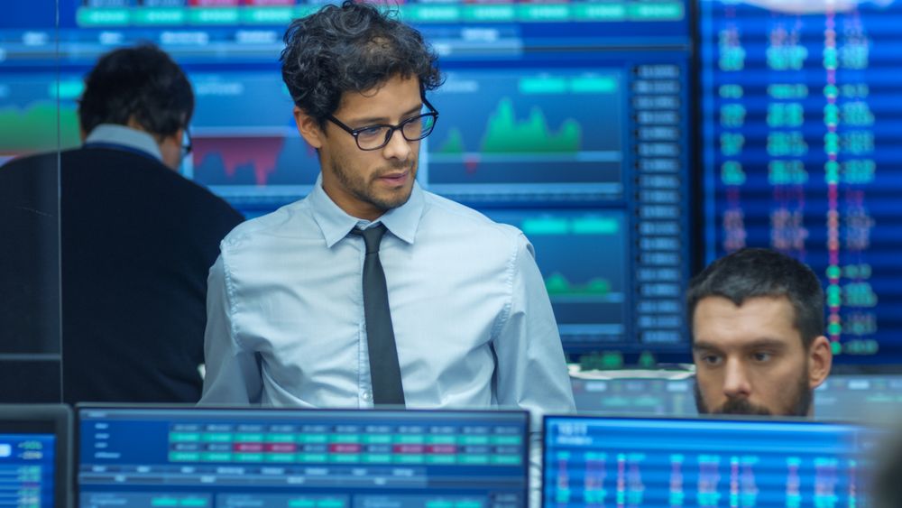 Stock Trader Inspects Others Work and Chat with Other.