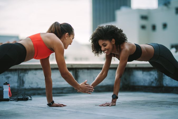 Cheerful women doing fitness workout together on rooftop
