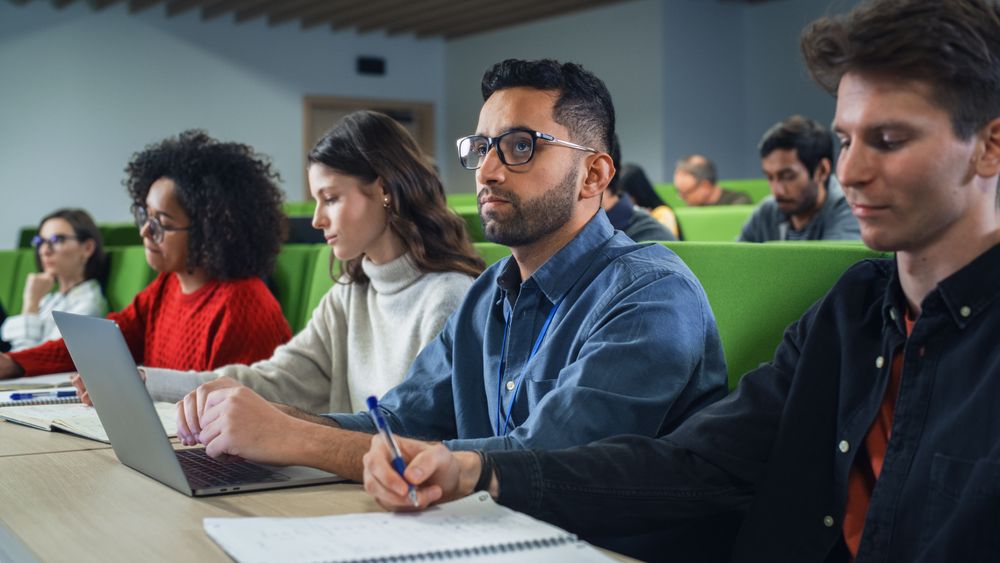 Male Student Studying in University with Diverse Multiethnic Classmates.