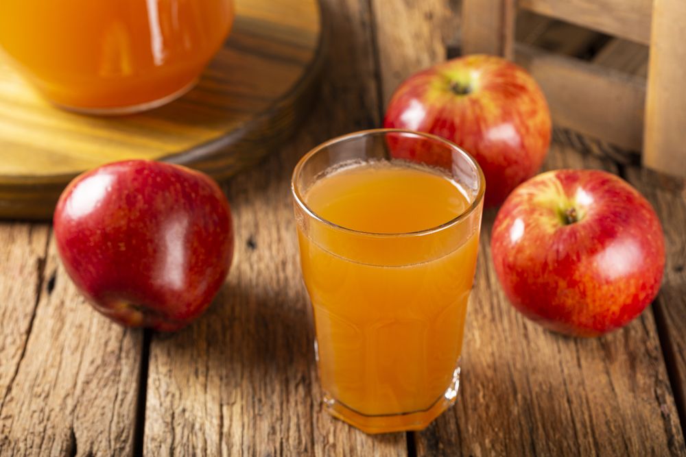 Apple juice and red apples on the table.