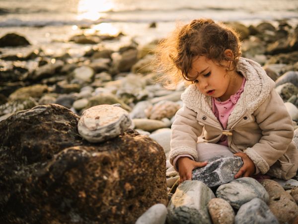 Girl sitting on rocky beach